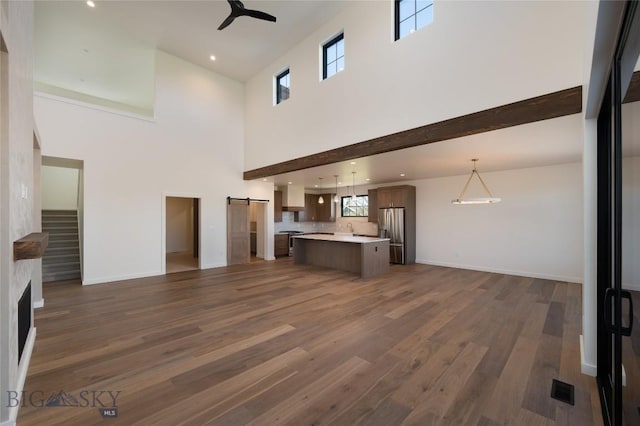 5680 Staffanson Rd, Bozeman, MT 59718 - unfurnished living room with a barn door, a high ceiling, a ceiling fan, wood finished floors, and baseboards