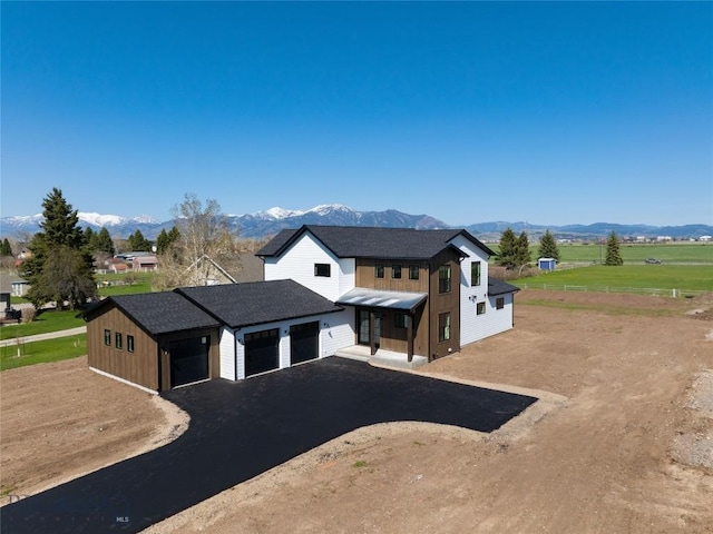 5680 Staffanson Rd, Bozeman, MT 59718 - modern farmhouse featuring a mountain view, dirt driveway, a shingled roof, board and batten siding, and an attached garage