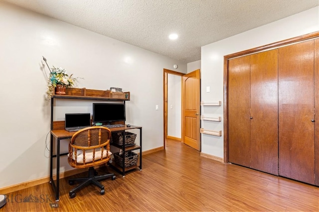office space with a textured ceiling, baseboards, and wood finished floors