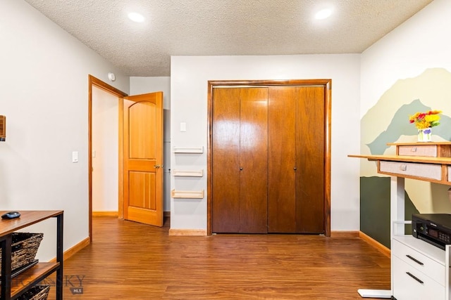 bedroom with a closet, recessed lighting, a textured ceiling, baseboards, and wood finished floors