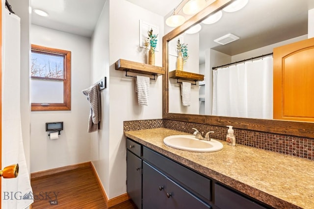 full bathroom featuring vanity, tasteful backsplash, visible vents, and wood finished floors