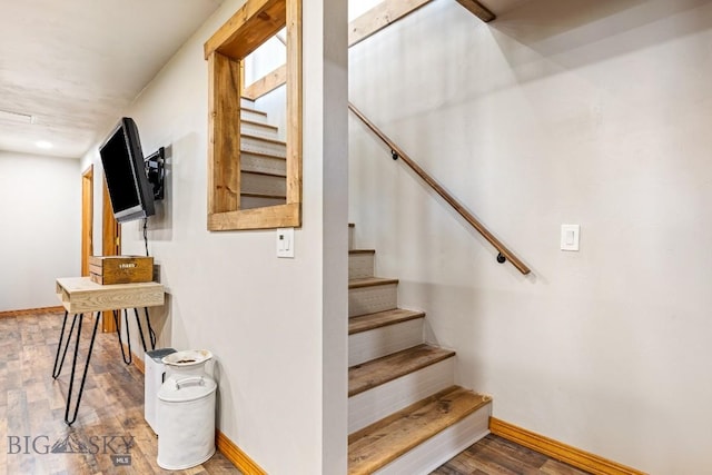 stairway with wood finished floors and baseboards