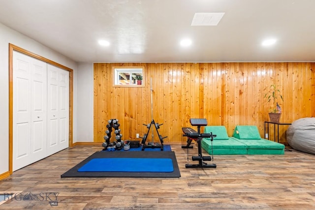 workout area featuring recessed lighting, baseboards, visible vents, wood walls, and wood finished floors