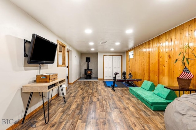 living area with wood finished floors, a wood stove, visible vents, recessed lighting, and wooden walls