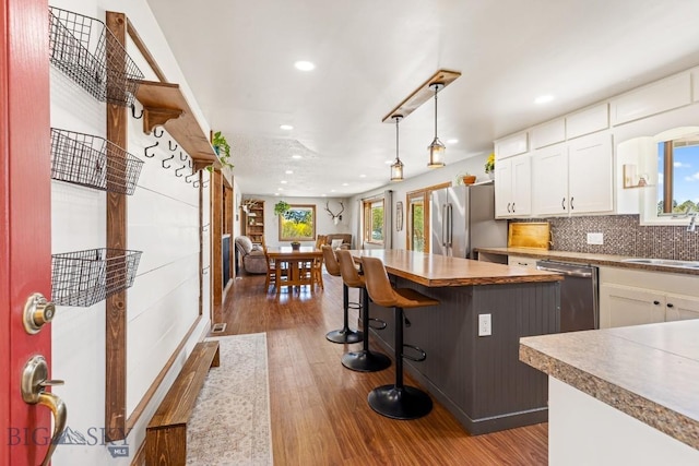 kitchen featuring a breakfast bar, a sink, white cabinets, appliances with stainless steel finishes, and recessed lighting