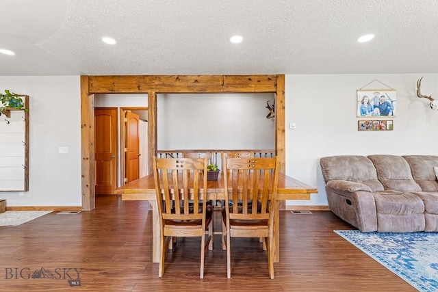 dining room with a textured ceiling, baseboards, and wood finished floors