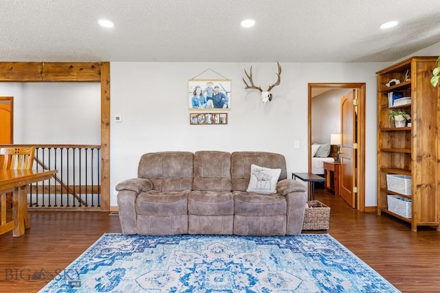 living room featuring a textured ceiling, baseboards, recessed lighting, and wood finished floors