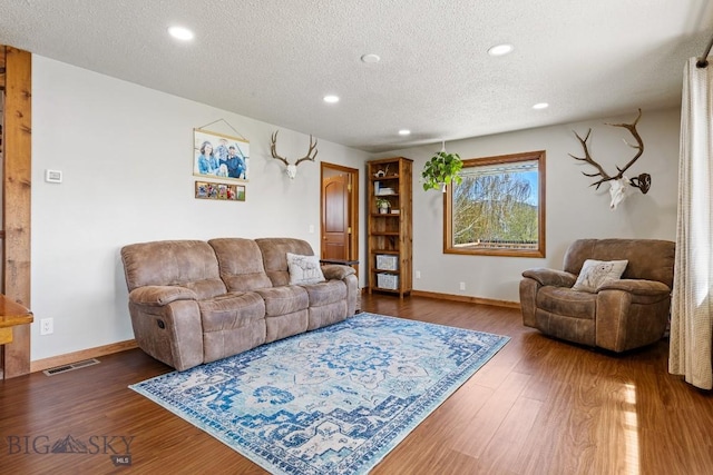 living room featuring a textured ceiling, visible vents, baseboards, and recessed lighting