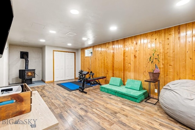 exercise area featuring a wood stove, wooden walls, wood finished floors, and recessed lighting