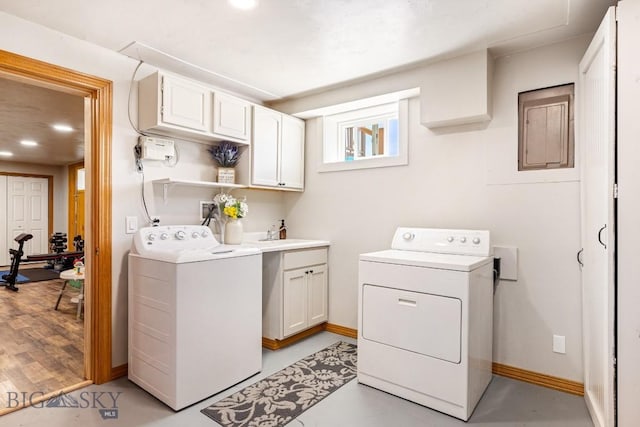 washroom featuring cabinet space, washing machine and clothes dryer, electric panel, and baseboards