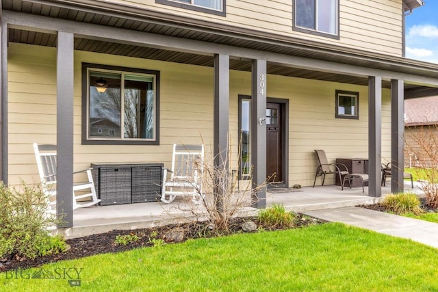 entrance to property with a porch, central AC, and a lawn