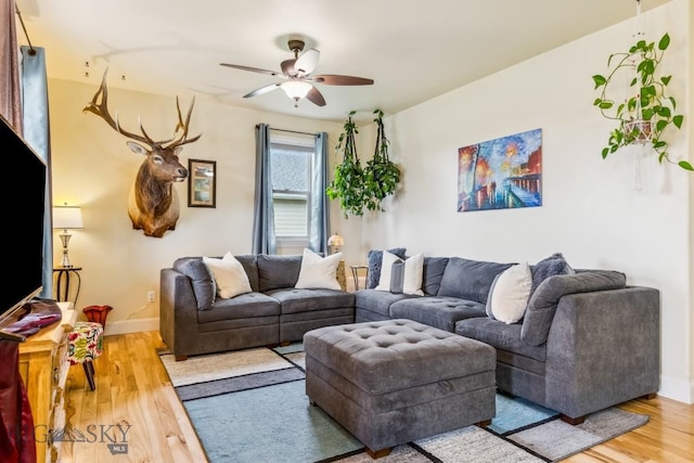 living area featuring a ceiling fan, wood finished floors, and baseboards