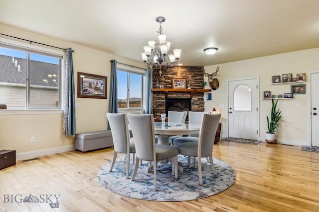 dining area featuring a chandelier, wood finished floors, baseboards, and a fireplace
