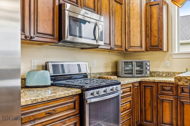 kitchen featuring stainless steel appliances and light stone counters