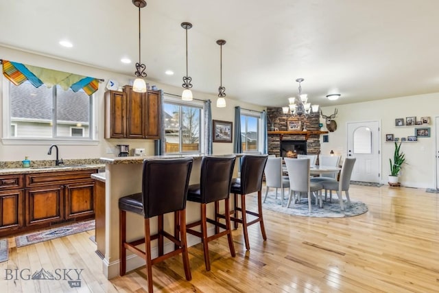 kitchen featuring a sink, light wood finished floors, a chandelier, a center island, and decorative light fixtures