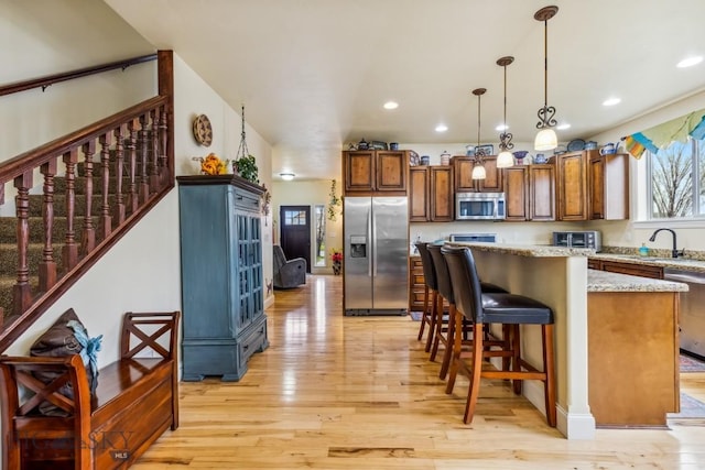 304 Farmall Ln, Manhattan, MT 59741 - kitchen featuring appliances with stainless steel finishes, light wood-type flooring, hanging light fixtures, a kitchen island, and a sink