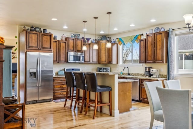 304 Farmall Ln, Manhattan, MT 59741 - kitchen featuring appliances with stainless steel finishes, light wood finished floors, a kitchen island, a kitchen breakfast bar, and decorative light fixtures