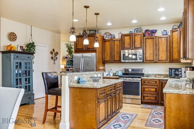 304 Farmall Ln, Manhattan, MT 59741 - kitchen with appliances with stainless steel finishes, light wood-style flooring, a center island, a kitchen bar, and recessed lighting