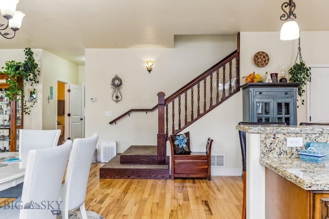 stairway with hardwood / wood-style flooring and a chandelier