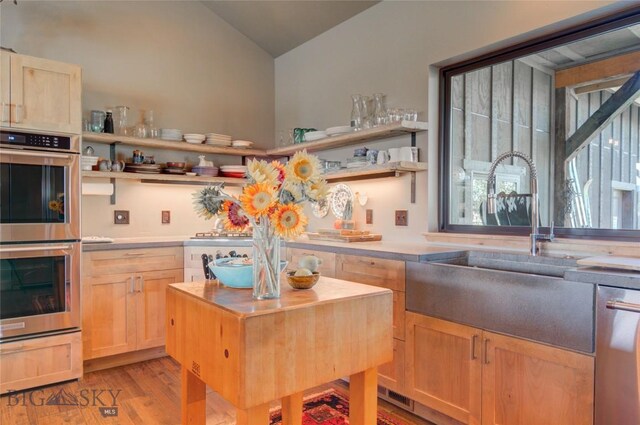 11762 Gooch Hill Rd, Gallatin Gateway, MT 59730 - kitchen featuring appliances with stainless steel finishes, open shelves, light brown cabinetry, vaulted ceiling, and light wood-style flooring
