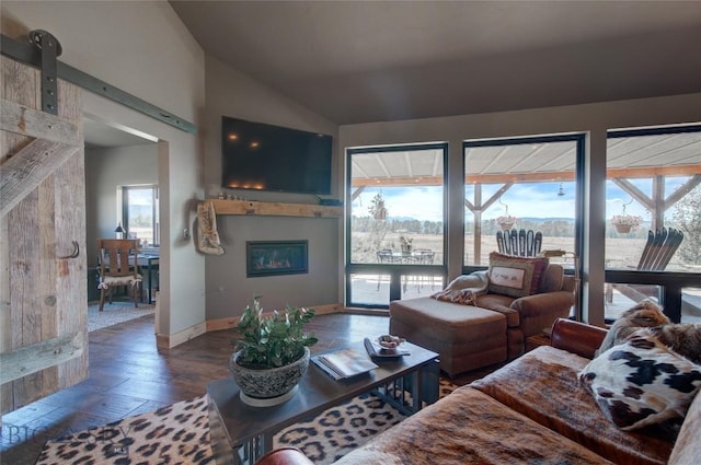 11762 Gooch Hill Rd, Gallatin Gateway, MT 59730 - living room featuring a barn door, vaulted ceiling, plenty of natural light, hardwood / wood-style flooring, and a glass covered fireplace