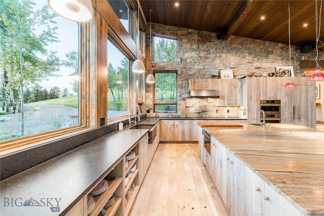 kitchen featuring wooden ceiling, a sink, light wood finished floors, light brown cabinets, and beam ceiling