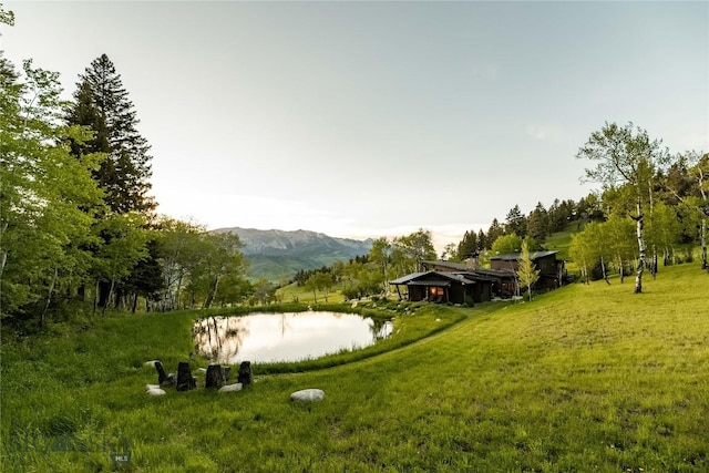 view of green lawn featuring a water and mountain view