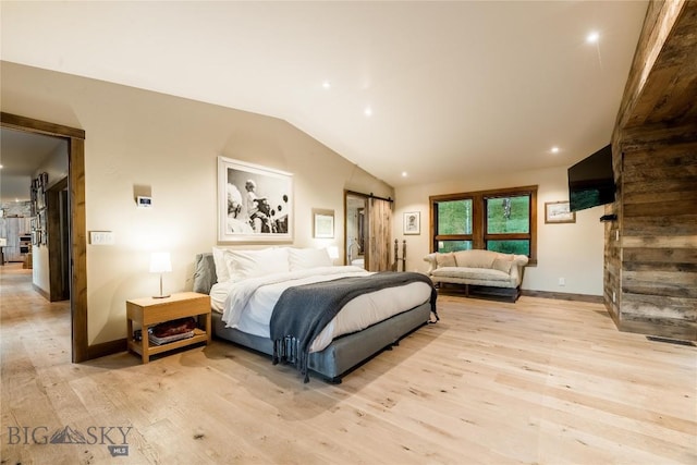 bedroom with light wood-style floors, vaulted ceiling, a barn door, baseboards, and recessed lighting