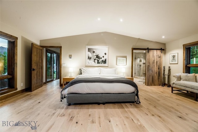 bedroom featuring a barn door, lofted ceiling, light wood-style floors, recessed lighting, and connected bathroom