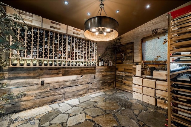 wine room featuring stone flooring, wood walls, recessed lighting, and lofted ceiling