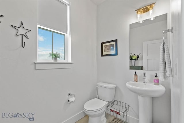 half bathroom with toilet and baseboards
