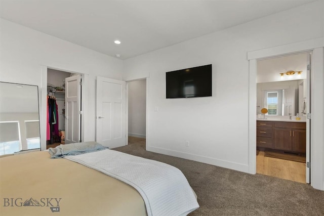 carpeted bedroom with a walk in closet, baseboards, ensuite bath, and a closet