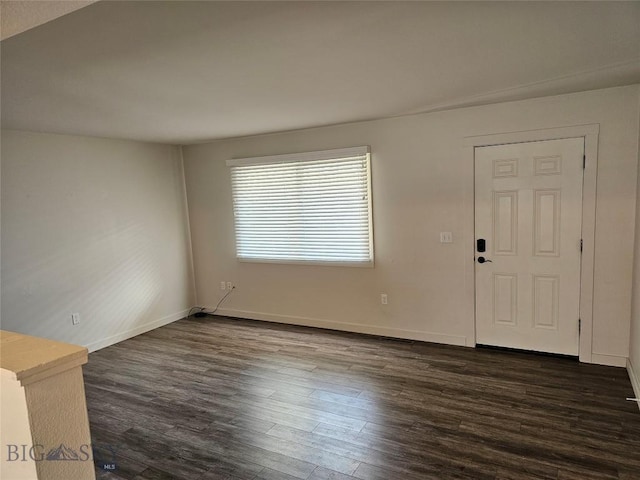 unfurnished living room featuring dark wood-style floors and baseboards