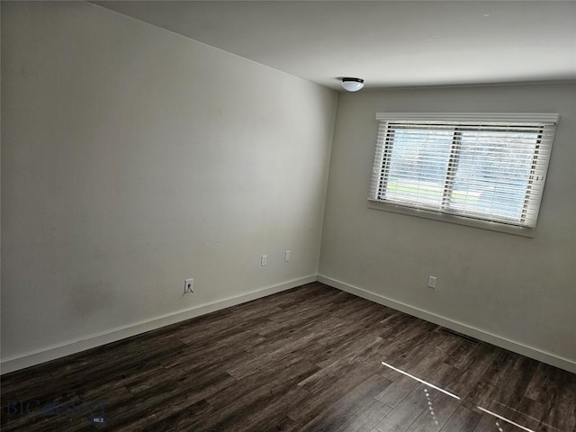 unfurnished room with dark wood finished floors and baseboards