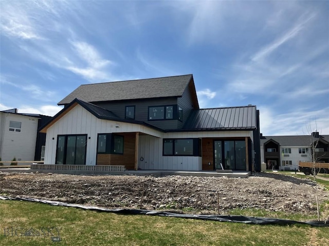 rear view of house featuring board and batten siding, a patio, and metal roof