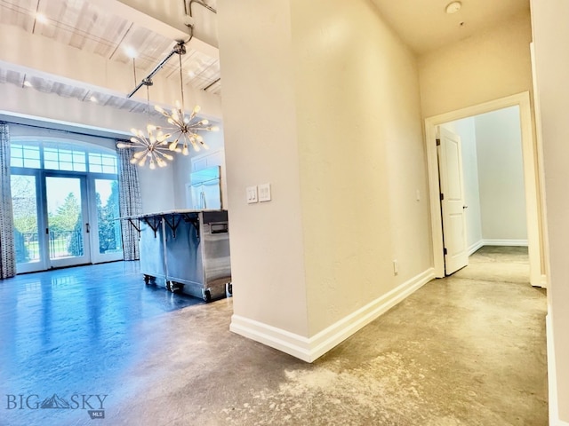hall featuring concrete floors, baseboards, a chandelier, and french doors