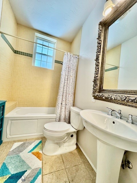 full bath with toilet, shower / bathtub combination with curtain, tile patterned floors, and baseboards