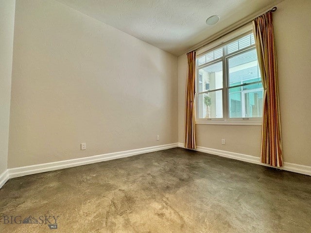 spare room featuring baseboards and dark colored carpet