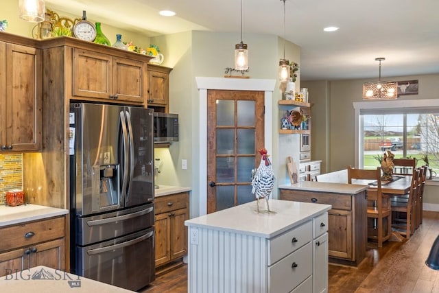 754 Milestone Dr, Belgrade, MT 59714 - kitchen with stainless steel appliances, brown cabinetry, dark wood-style flooring, a center island, and light countertops