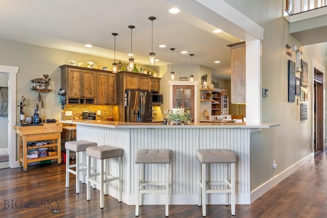 754 Milestone Dr, Belgrade, MT 59714 - kitchen featuring stainless steel appliances, brown cabinetry, dark wood-style flooring, backsplash, and recessed lighting