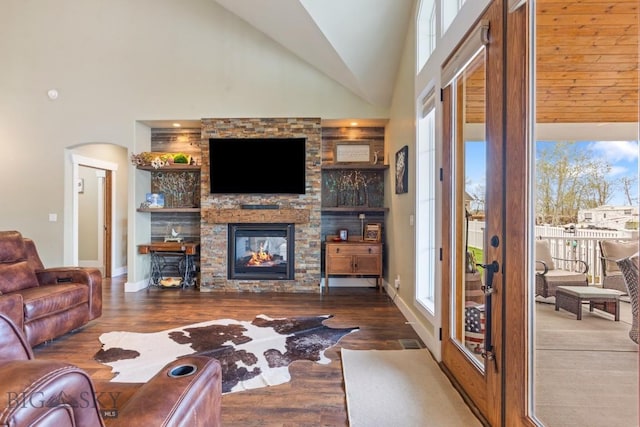 754 Milestone Dr, Belgrade, MT 59714 - living room featuring wood finished floors, a fireplace, baseboards, arched walkways, and high vaulted ceiling