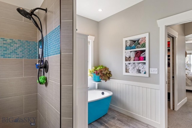 754 Milestone Dr, Belgrade, MT 59714 - bathroom with tiled shower, a soaking tub, wainscoting, and wood finished floors