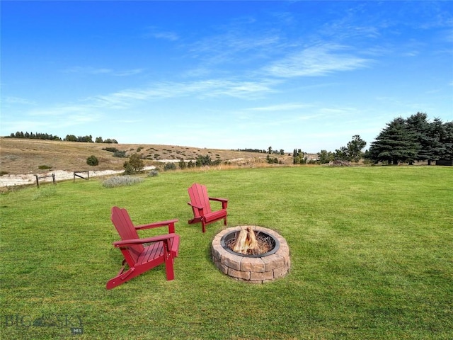 view of grassy yard featuring a fire pit and a view of rural / pastoral area