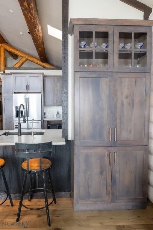 kitchen with a kitchen bar, glass insert cabinets, and light wood-style flooring