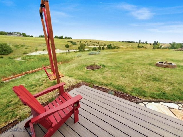 deck with a fire pit, a view of countryside, and a lawn
