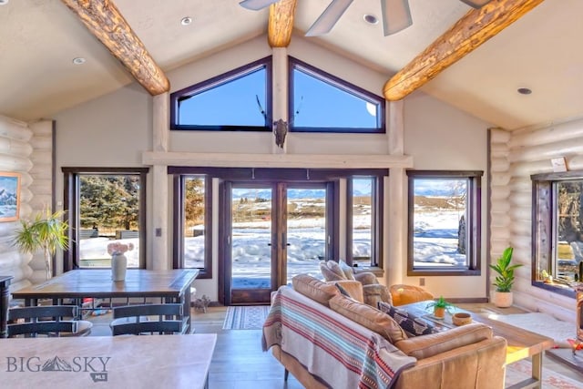 living room with log walls, ceiling fan, wood finished floors, and plenty of natural light