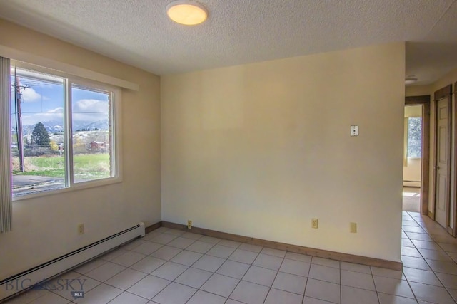 spare room featuring a baseboard heating unit, a textured ceiling, light tile patterned flooring, and baseboards
