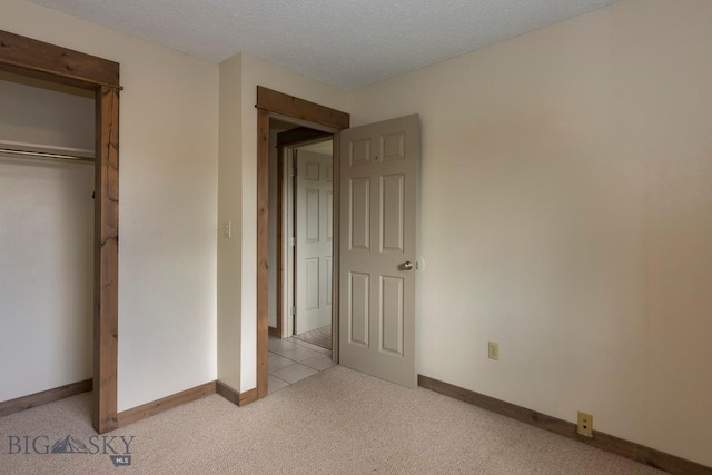 unfurnished bedroom featuring carpet floors, baseboards, a closet, and a textured ceiling
