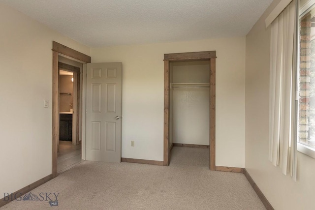 unfurnished bedroom with carpet floors, a textured ceiling, and baseboards