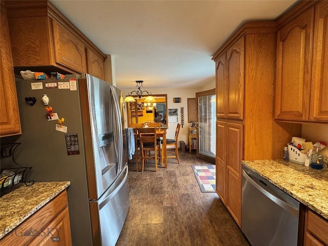 105 Country Club Ln, Butte, MT 59701 - kitchen featuring stainless steel appliances, brown cabinets, light stone countertops, dark wood-type flooring, and a chandelier